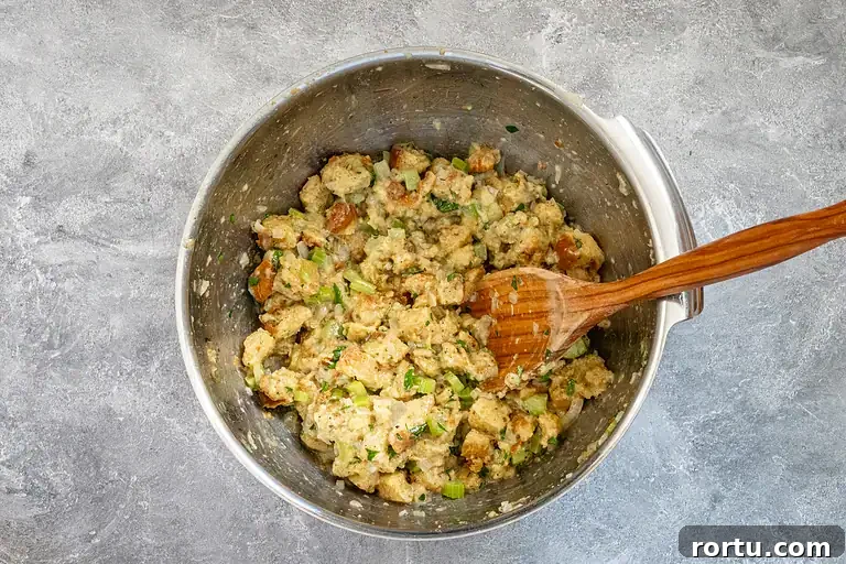 Cooked stuffing mixture with celery and herbs in a metal bowl.