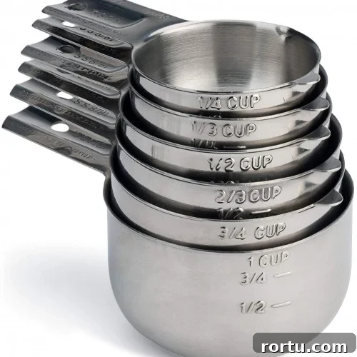 A nested stack of stainless steel measuring cups, each labeled with different measurements.