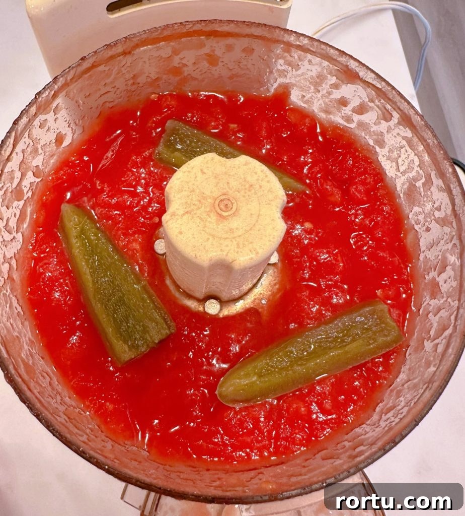 Add jalapeños to processed tomatoes in the food processor.
