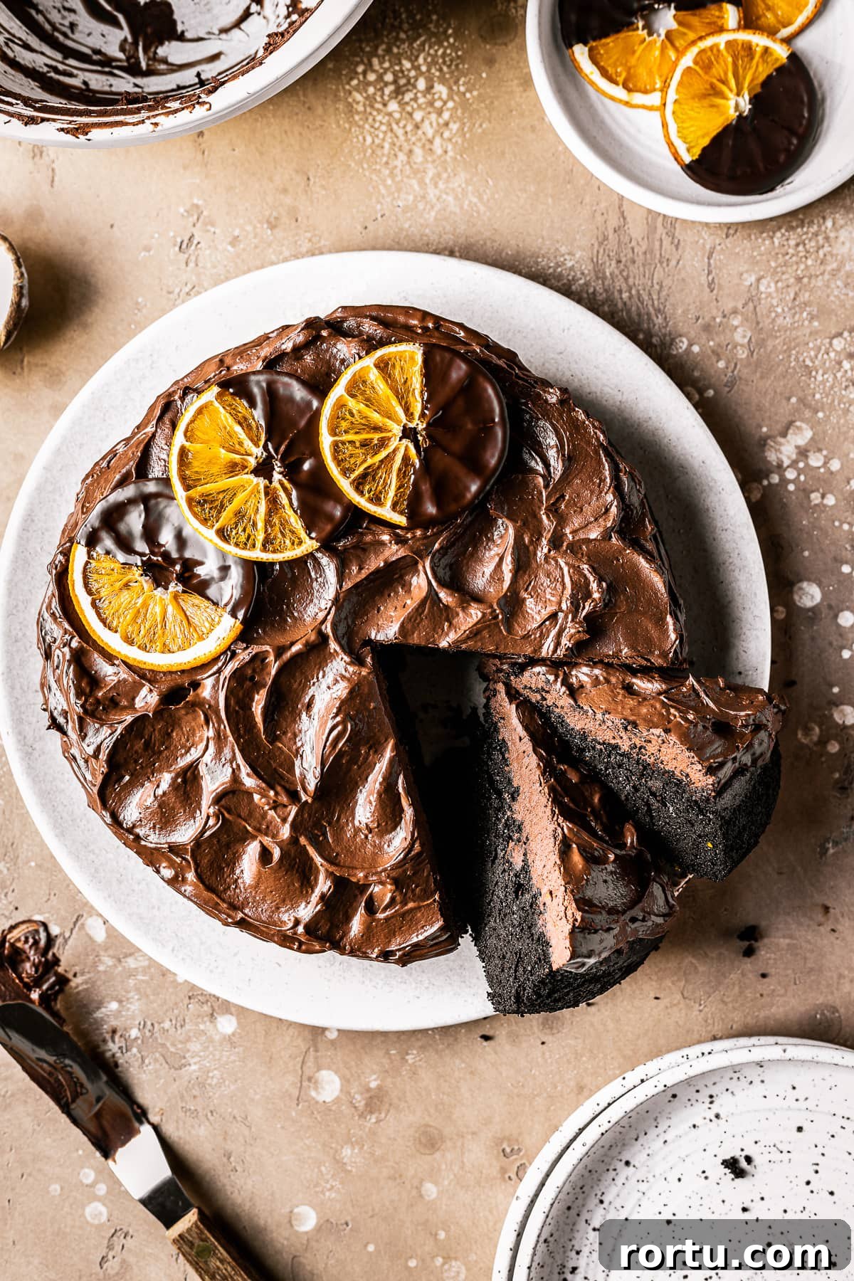 A chocolate cake with two slices cut and tipped revealing the dark interior and fudgy chocolate frosting. 