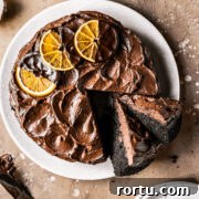 A chocolate cake with two slices cut and tipped revealing the dark interior and fudgy chocolate frosting.