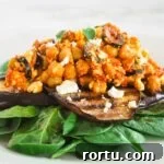 A side view of a plate with spinach topped with grilled eggplant and chickpea salad.