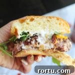 Meet the ultimate stuffed burger to rule your BBQ!!! This juicy stuffed burger oozes with melted cheeses and is topped with crispy bacon and peppery arugula
