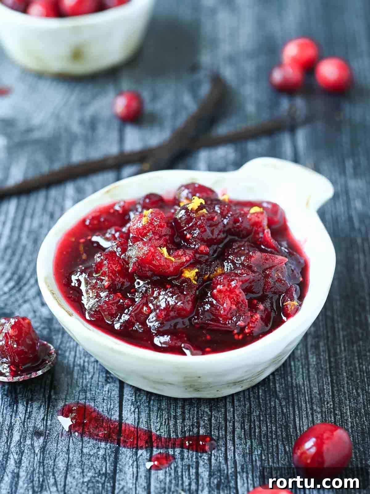 Small white bowl of cranberry compote on a grey surface.