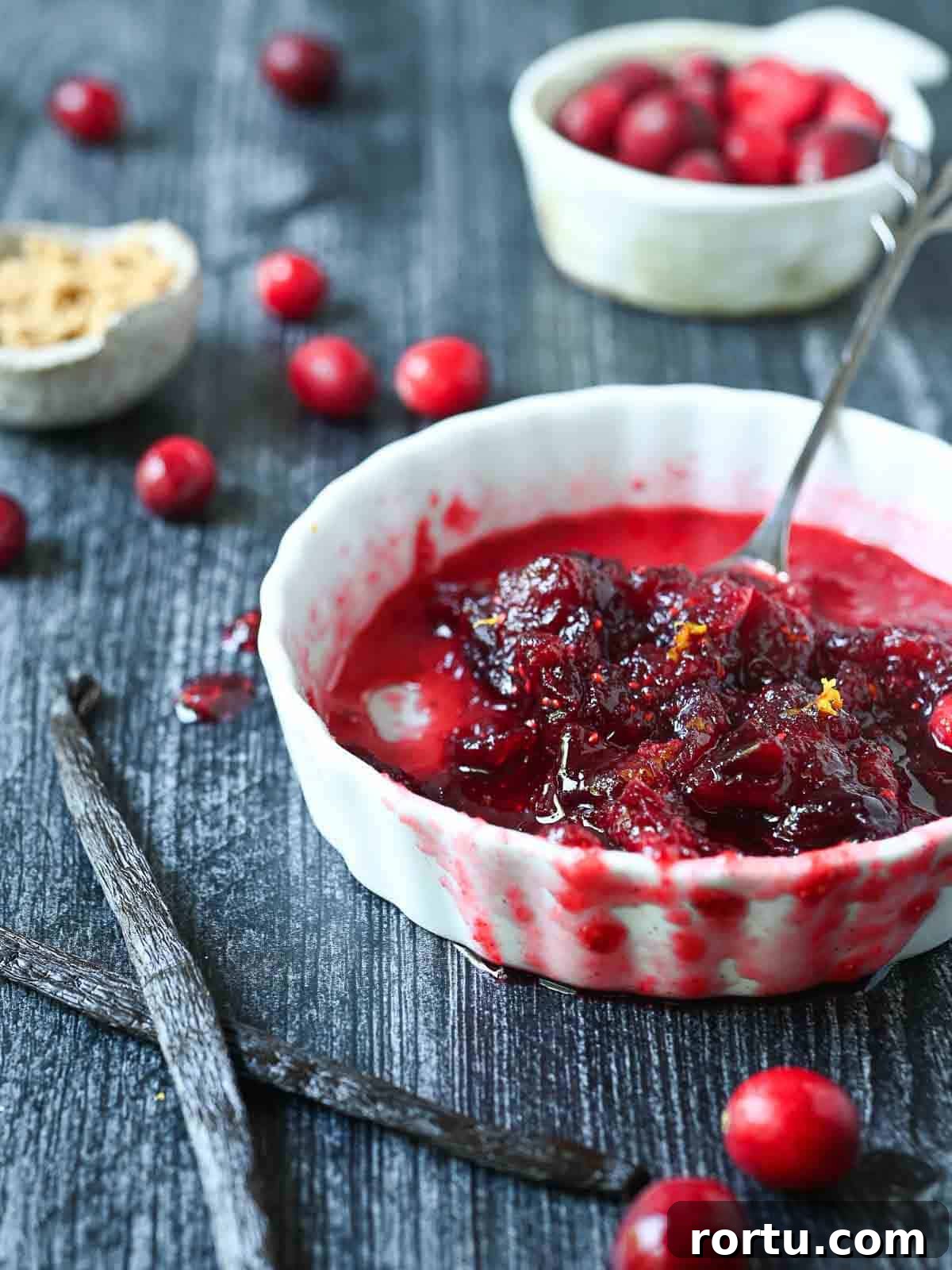 Half-eaten bowl of cranberry compote with vanilla beans in a white bowl.