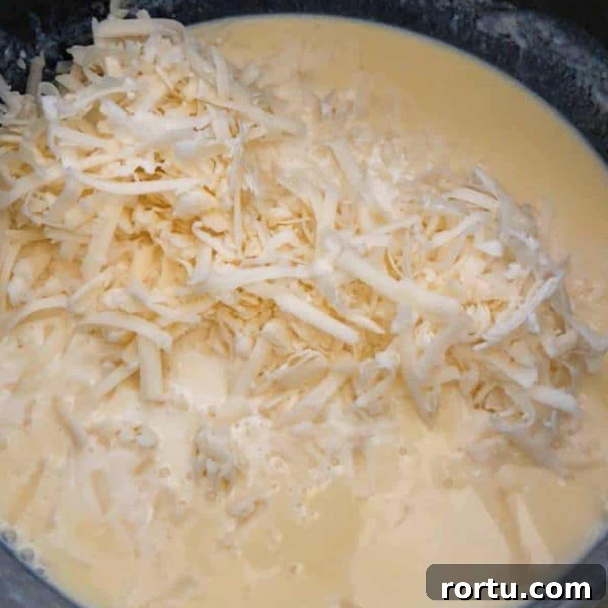 Creamy White Cheddar Macaroni and Cheese Recipe 7 Cheese in roux in skillet macaroni and cheese.