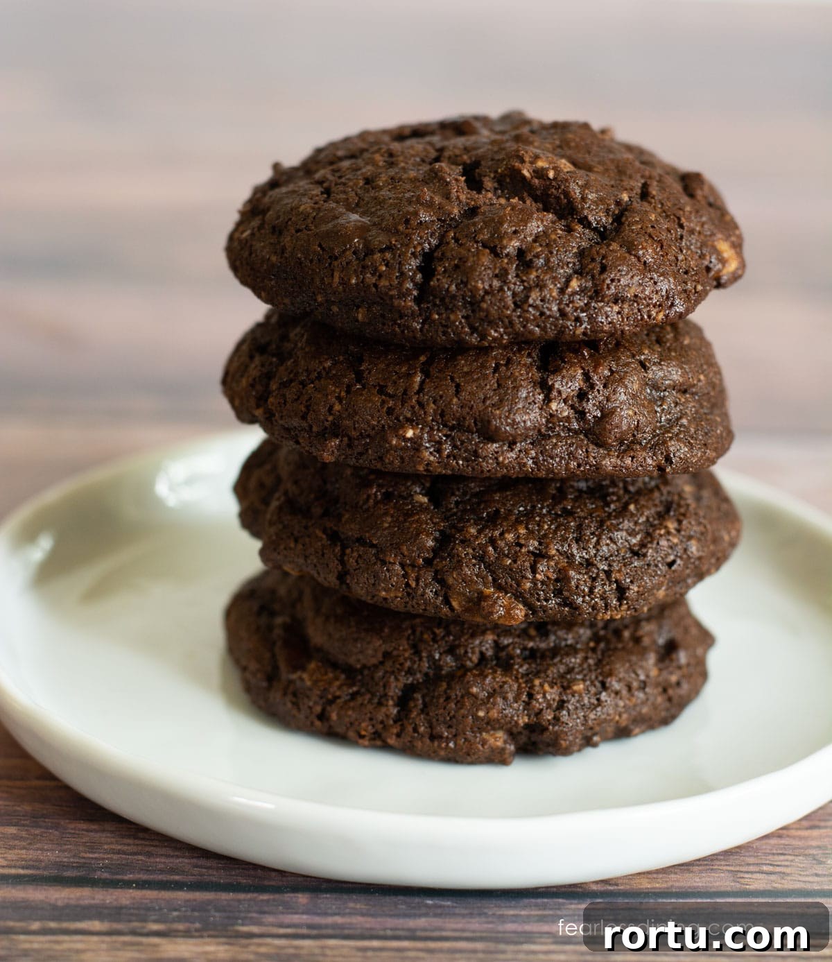 A stack of four double chocolate gluten free cake mix cookies on a small white plate.