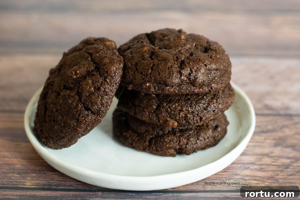 A stack of three cookies on a small white plate. Another cookie is leaning on the stack.