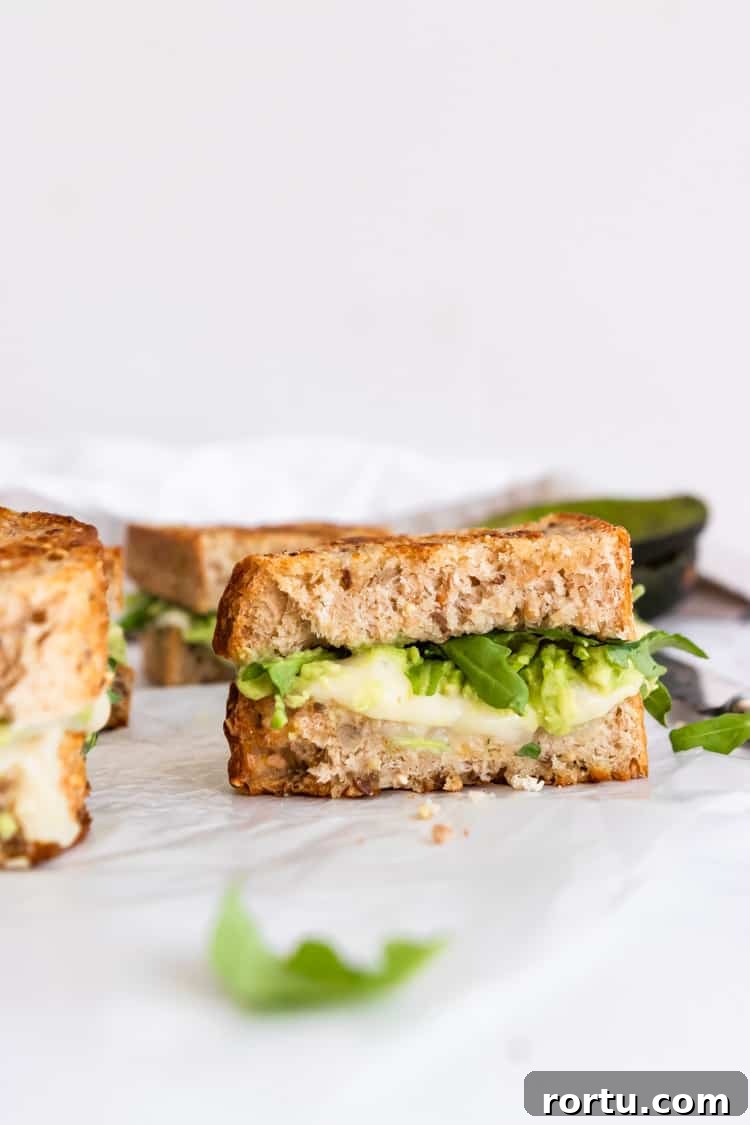 Half of a havarti grilled cheese with avocado and arugula.