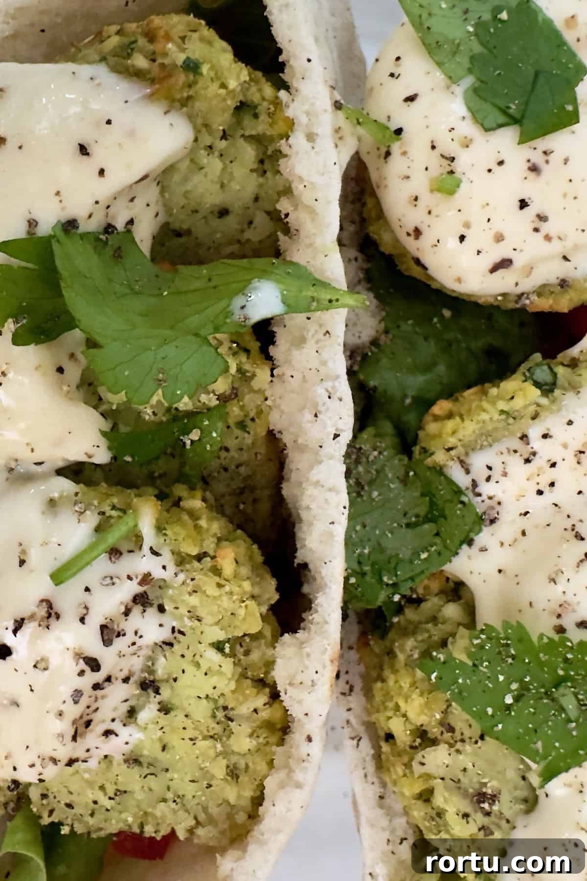 Air fryer falafel stuffed in a pita with sauce and fresh greens.