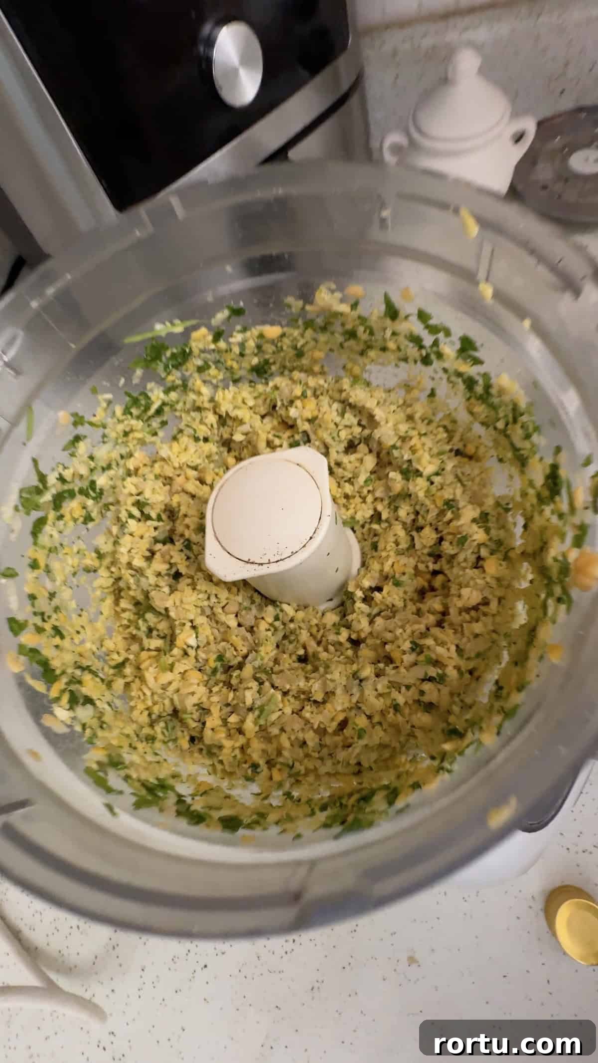 Blending chickpeas, fresh herbs, and seasonings in a food processor to make falafel.