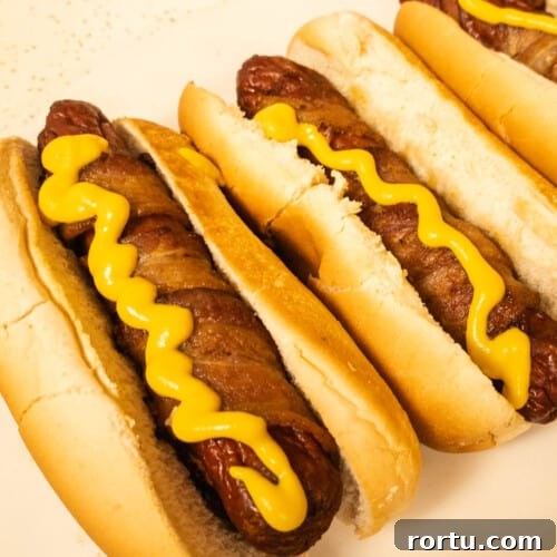 Bacon wrapped hot dog ready to eat with some yellow mustard
