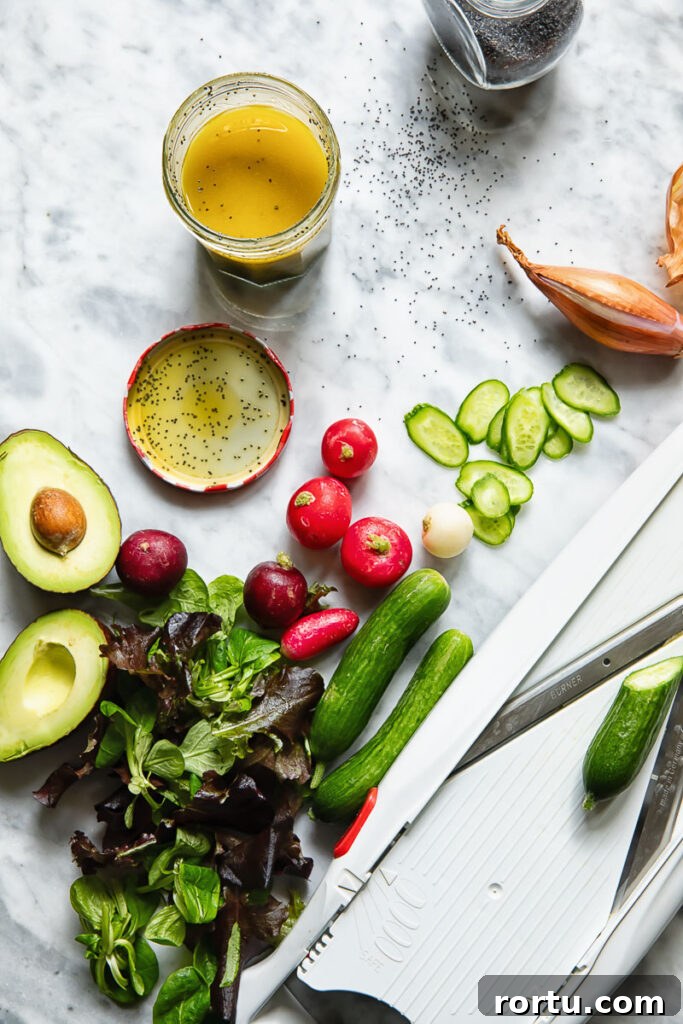 Creamy Poppy Seed Dressing Recipe for Salads and Slaws 3 Top down shot of a jar of poppyseed salad dressing next to radish and cucumber slices and half an avocado