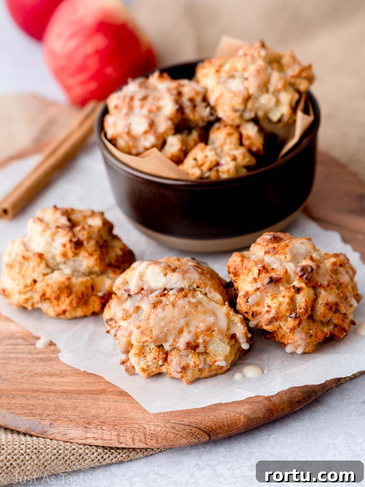 Glazed apple fritters in a bowl and on parchment paper. 