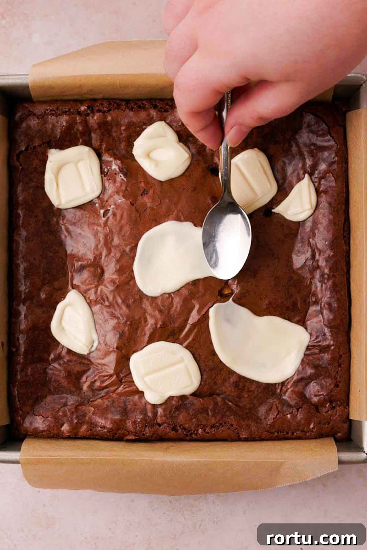 Mini Egg Chocolate Brownies with Melted Candy Centers 11 smearing melted white chocolate with the back of a spoon onto baked brownie top