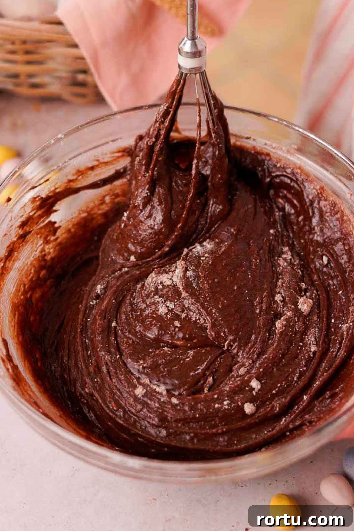 Mini Egg Chocolate Brownies with Melted Candy Centers 8 folding brownie batter with a whisk in glass bowl