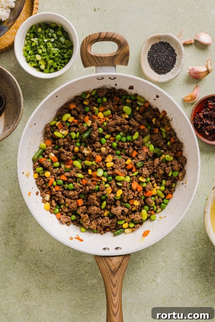 Savory Ground Beef Fried Rice Recipe for Weeknight Dinners 6 Ground beef cooked with vegetables in a pan.