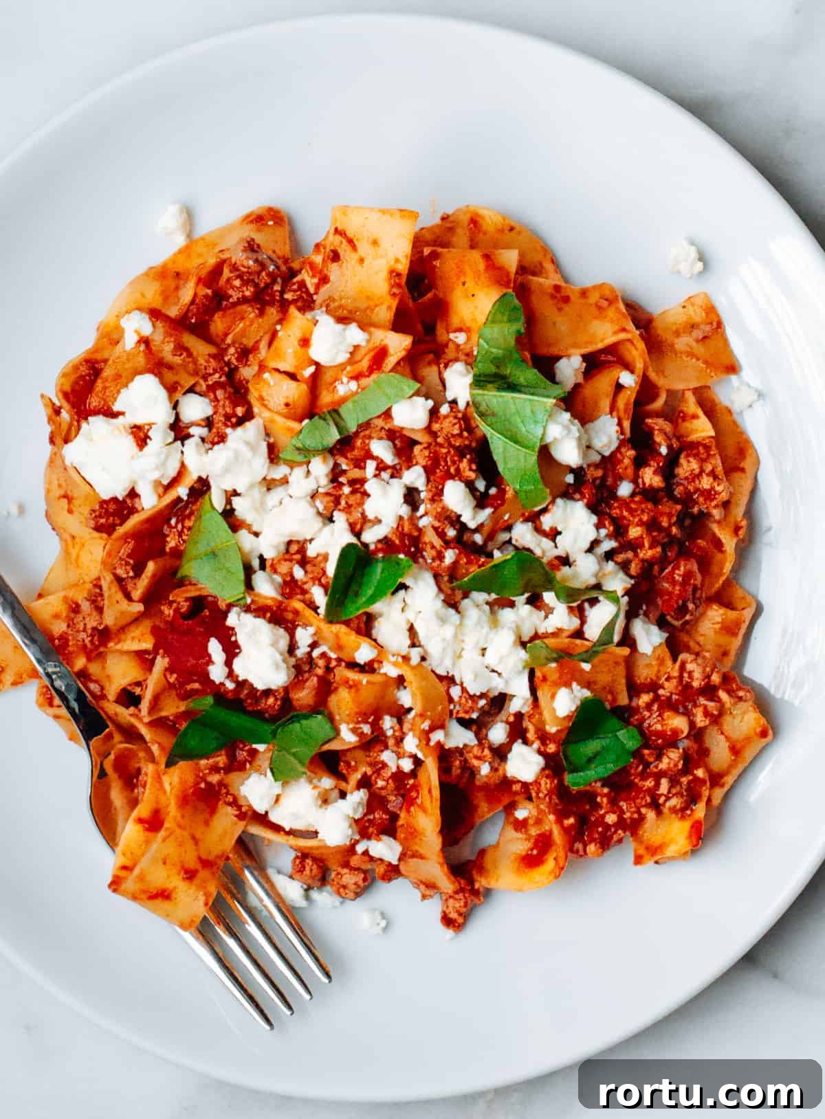 Lamb Ragu Recipe: Slow-Simmered Sauce with Parmesan 4 Lamb Ragu with pasta on a white plate photographed from the top.