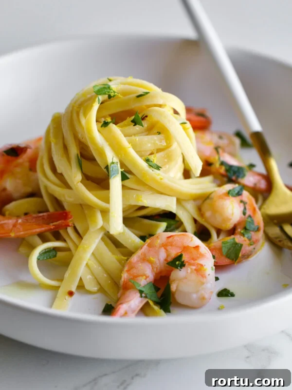 10-Minute Blackened Shrimp Recipe for Flavorful Weeknight Meals 14 Shrimp scampi pasta on a plate with parsley and a fork.