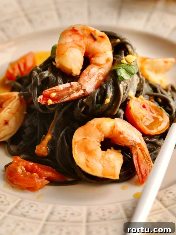 10-Minute Blackened Shrimp Recipe for Flavorful Weeknight Meals 16 Fork on a plate with squid ink pasta with seafood and cherry tomato sauce.