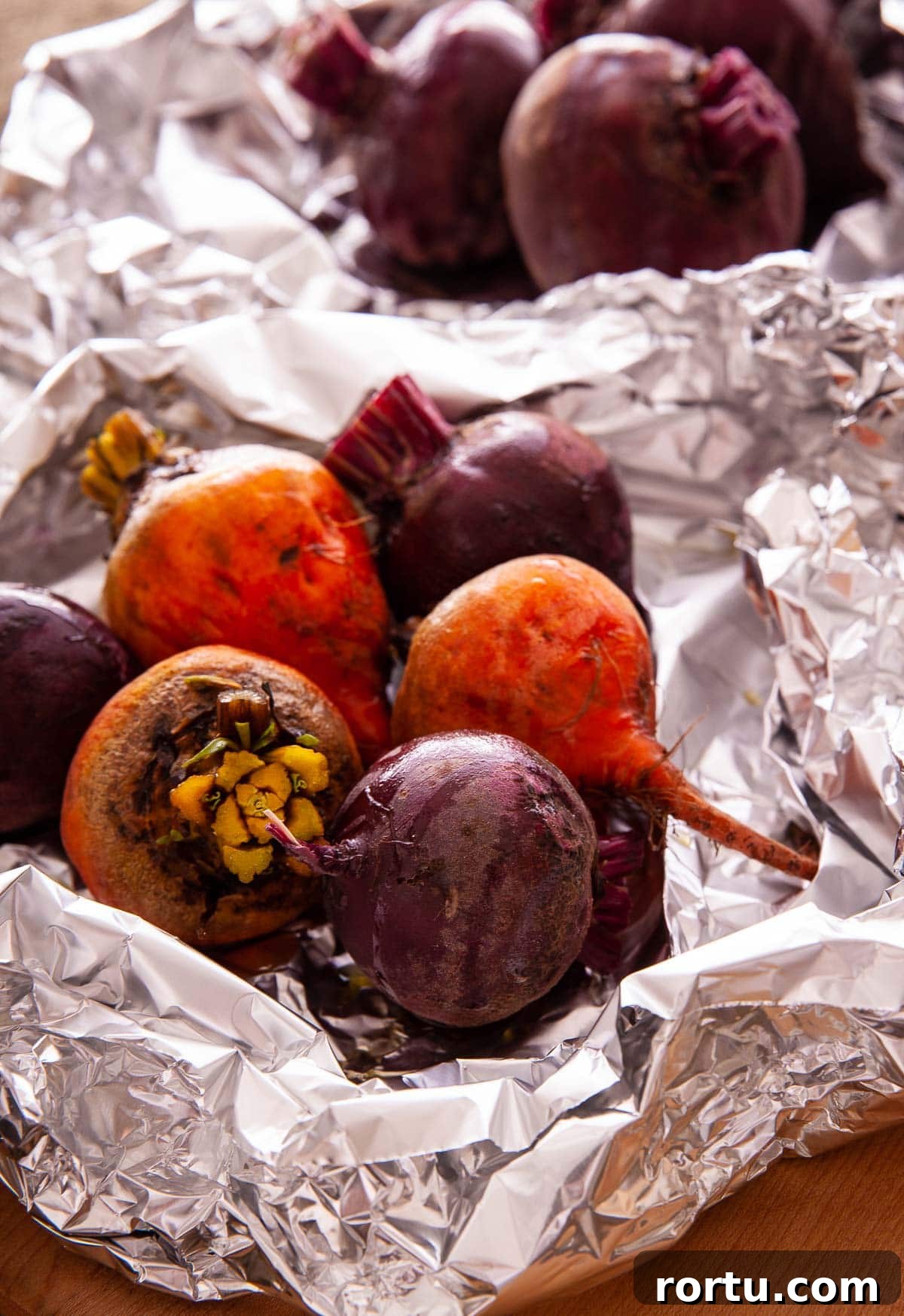 Red and gold beets roasting in aluminum foil with oil.