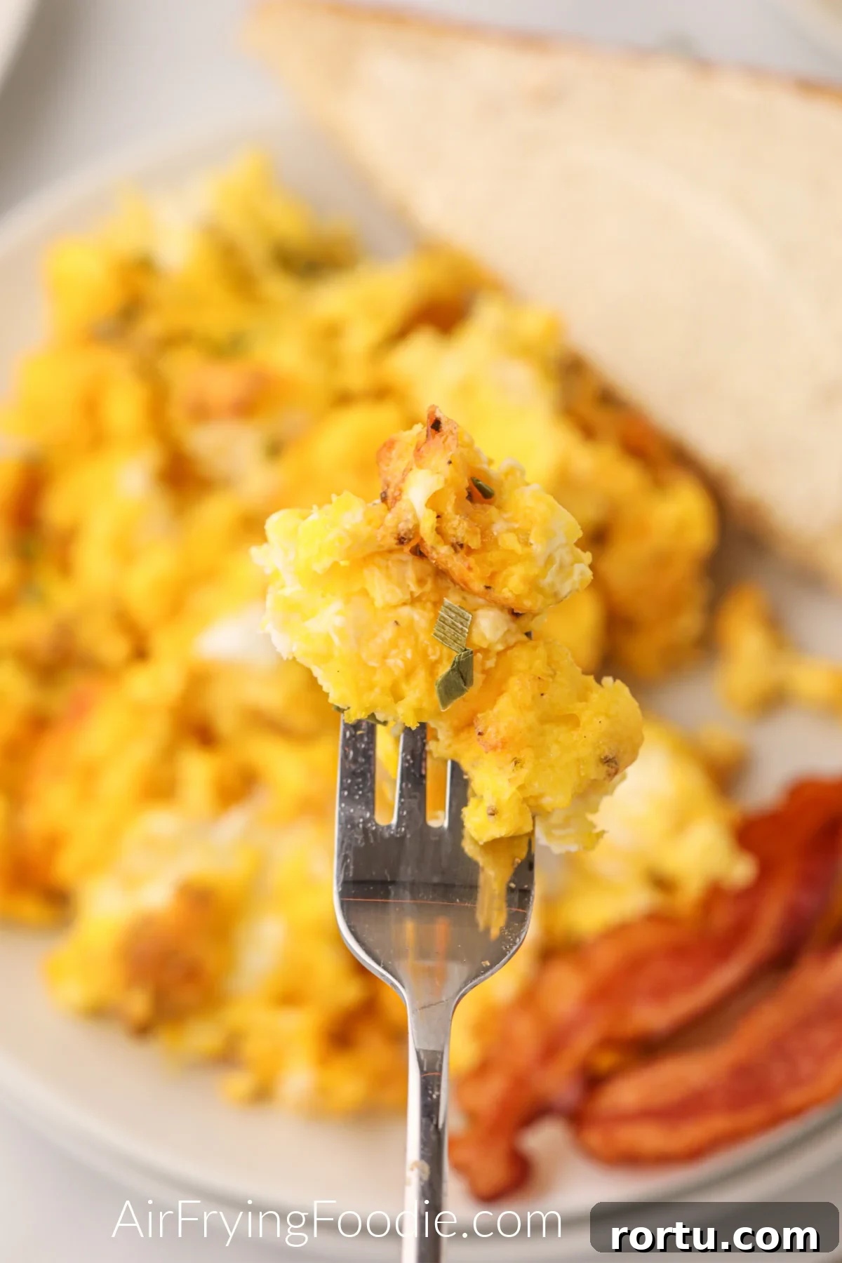 A bite of air fried scrambled eggs on a fork ready to eat.