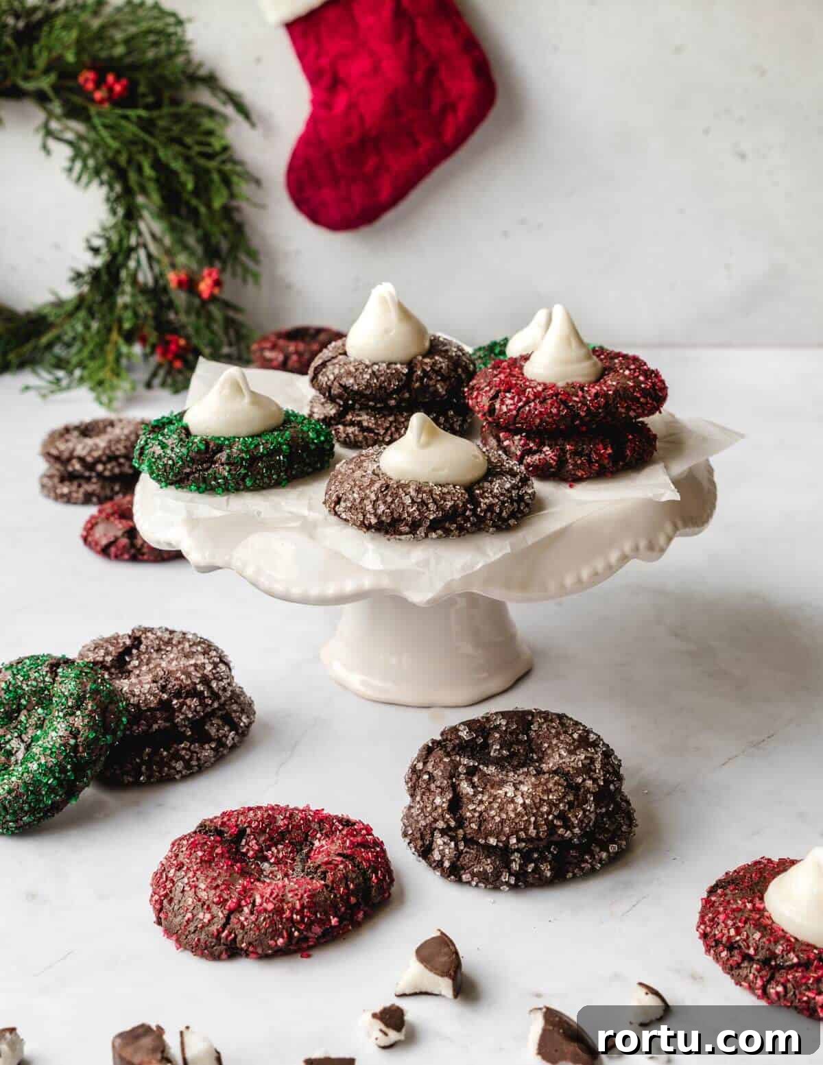 Festive chocolate thumbprint cookies filled with peppermint schnapps filling on a cake stand.