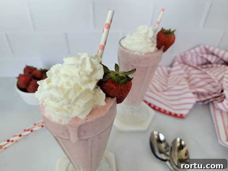 Strawberry milkshakes with whipped cream and fresh strawberries in shake glasses