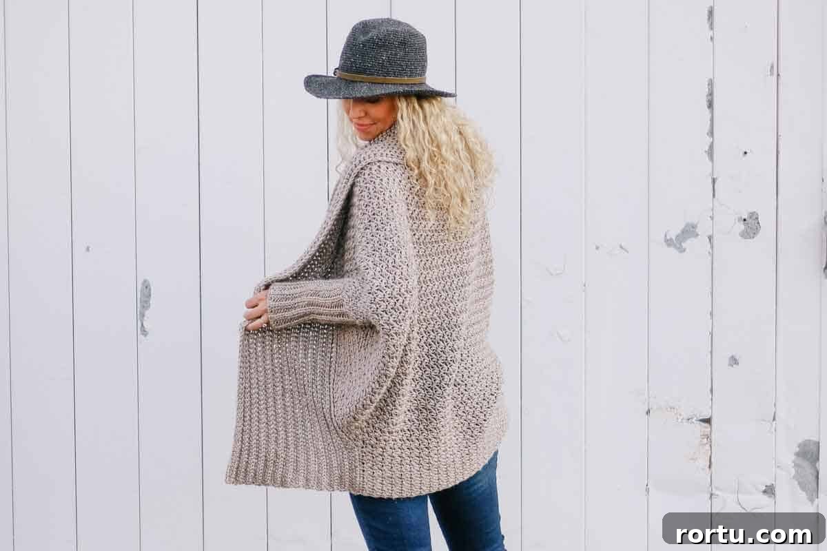 Image shows a blonde woman wearing a DIY crochet sweater standing in front of a wooden wall. -Skip To My Lou