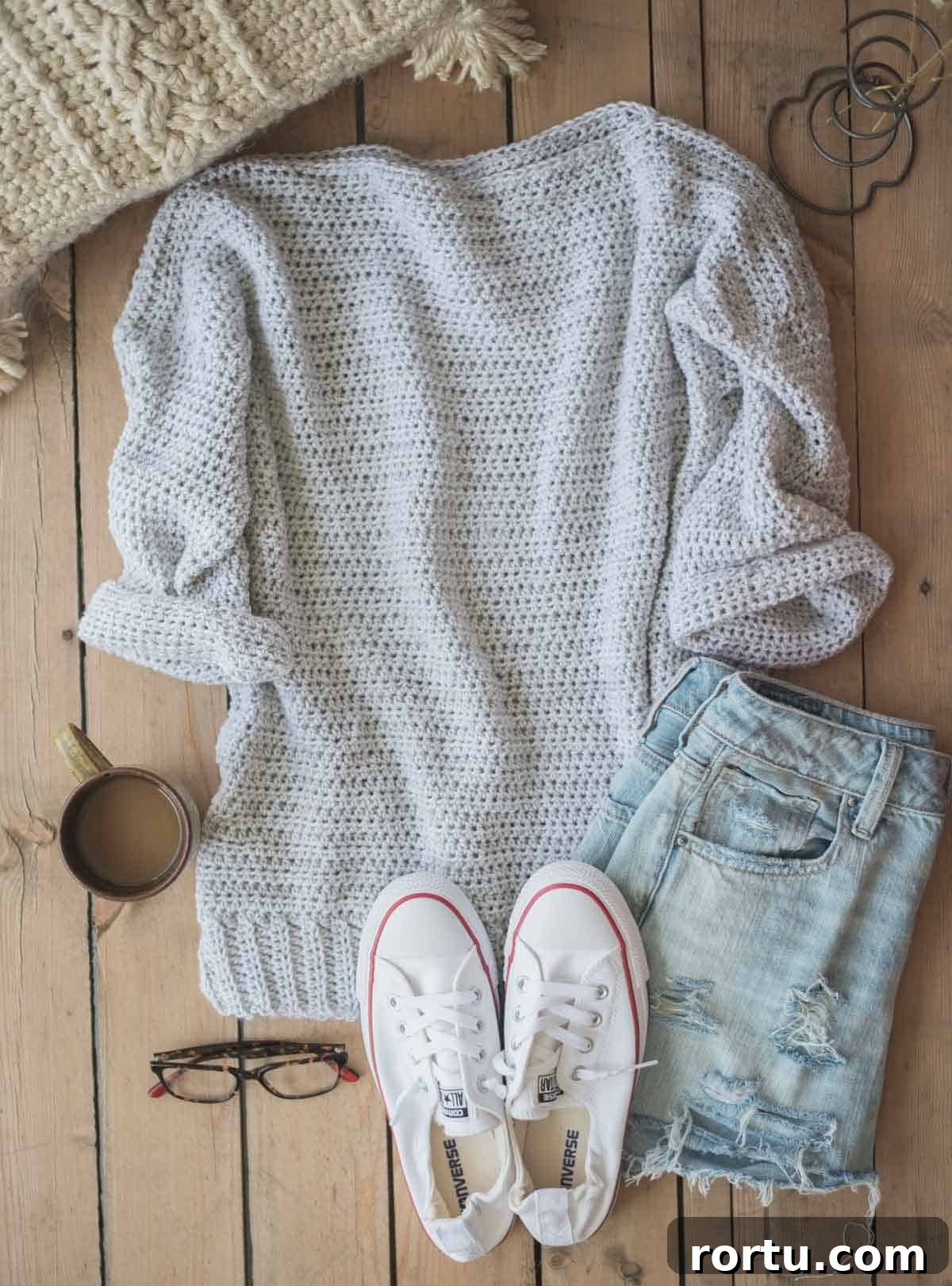 Image shows an oversized crochet sweater laying flat with jeans and tennis shoes at the side. -Skip To My Lou
